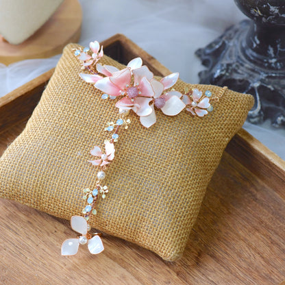 Elvyne white resin floral hand harness with soft pink centres laid on a jute cushion
