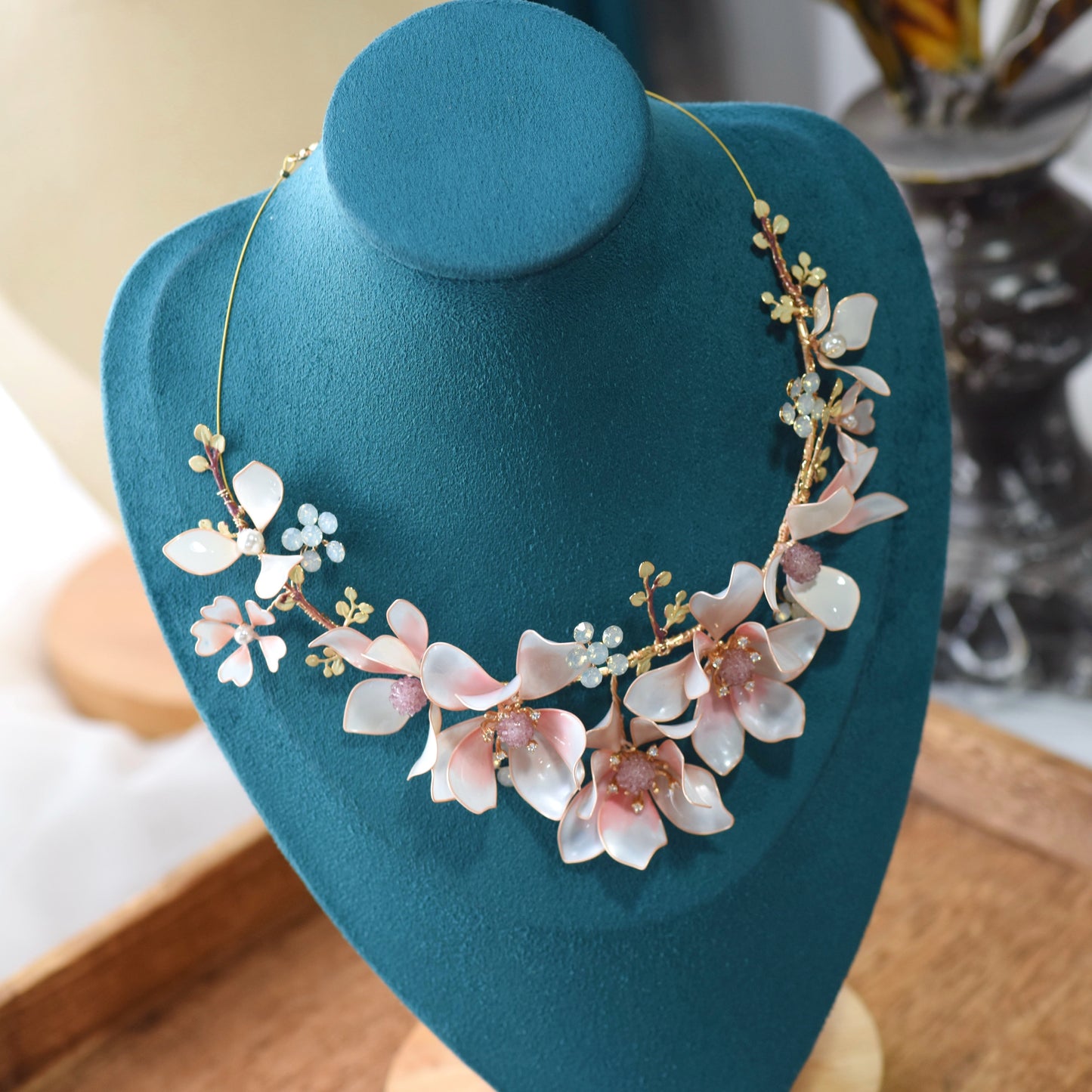 Elvyne white and pink resin floral statement necklace displayed on a stand showing the garland design
