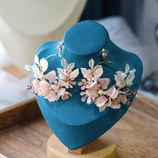 Eos blush pink resin floral earrings with ivory accents displayed on a stand
