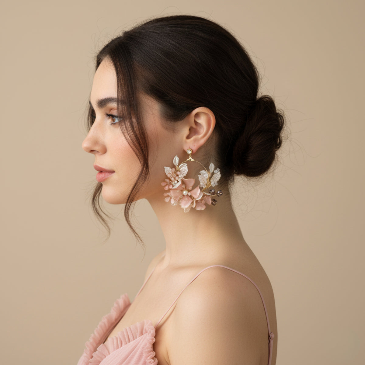 Side profile of model wearing Eos blush pink floral statement earrings with a low bun
