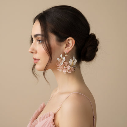 Side profile of model wearing Eos blush pink floral statement earrings with a low bun
