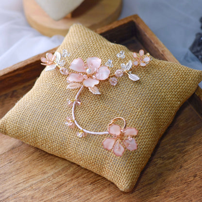 Eos blush pink resin floral hand harness with golden trail and purple bead accents on a jute cushion
