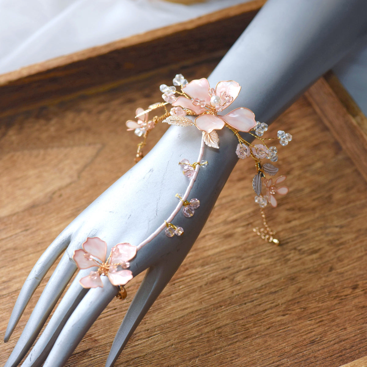 Eos blush pink floral hand harness on a display hand showing the wrist-to-finger vine design
