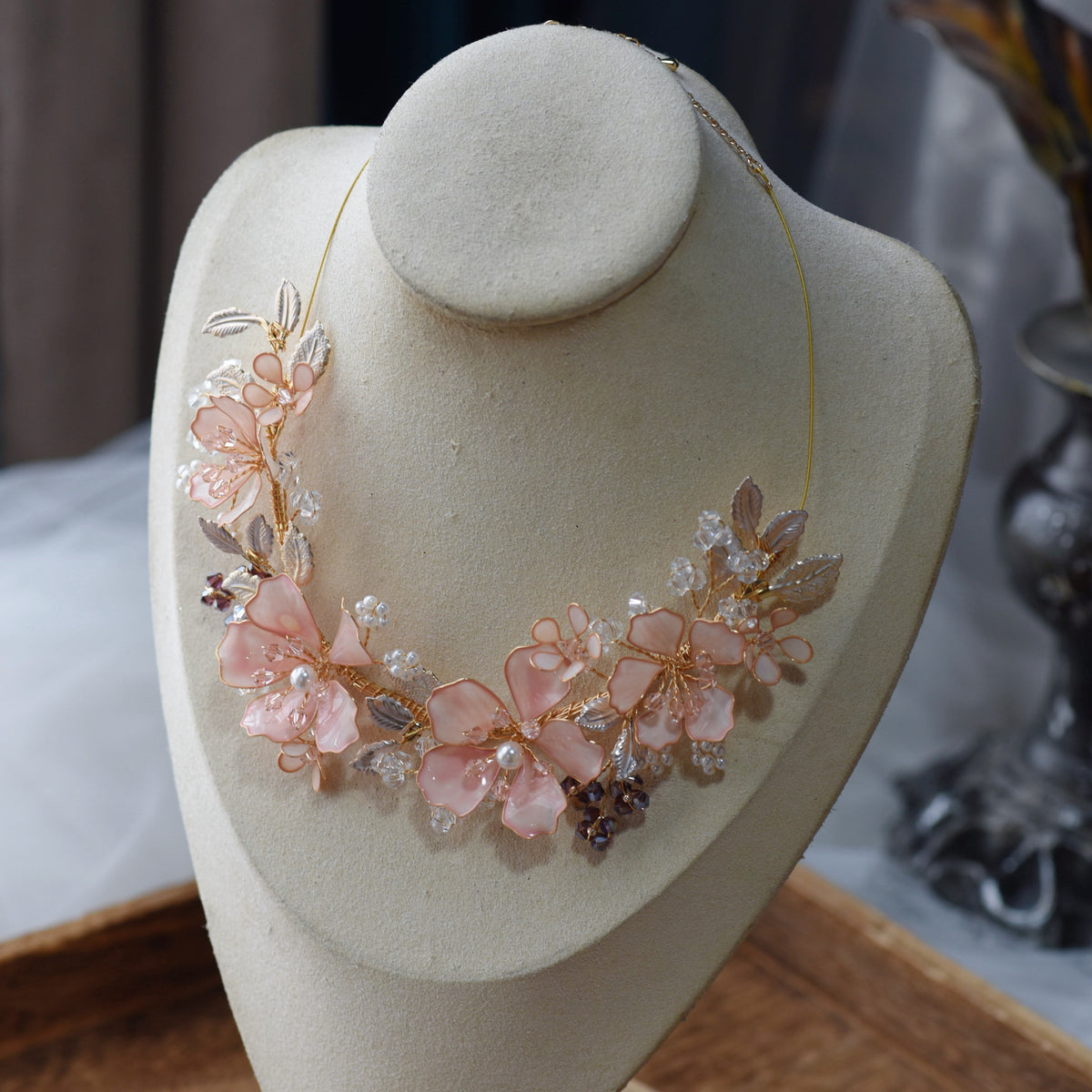 Eos blush pink floral statement necklace displayed on a stand showing the garland-style bloom arrangement
