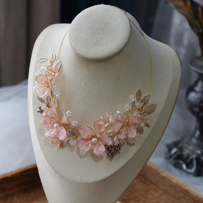 Eos blush pink floral statement necklace displayed on a stand showing the garland-style bloom arrangement
