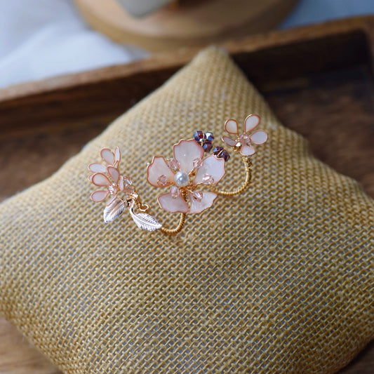Eos blush pink resin floral statement ring with purple bead accents on a jute cushion
