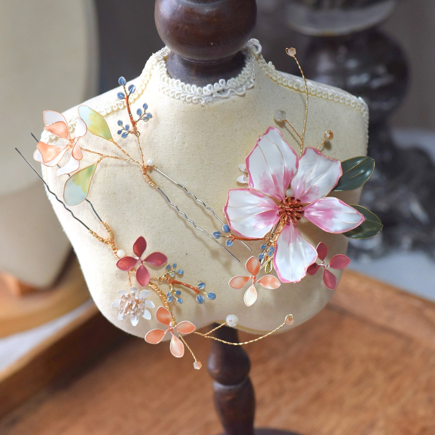 Close-up of Esmeralda floral hair accessory showing translucent resin petals, pastel foliage and intricate gold wirework