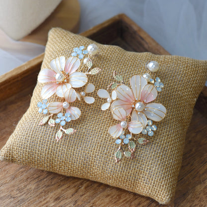 Florence blush pink and white resin floral statement earrings with mint accents on a jute cushion
