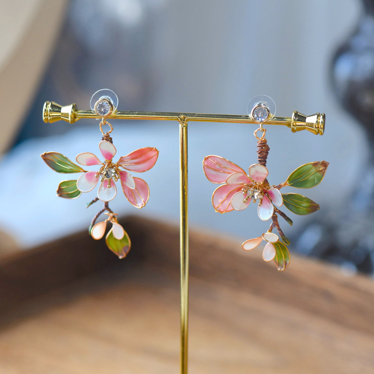 Florentine blush pink and olive resin floral earrings on a display stand
