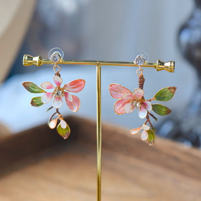 Florentine blush pink and olive resin floral earrings on a display stand
