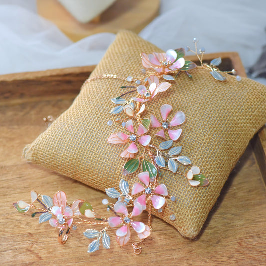 Florentine long blush pink resin floral hand harness with olive leaves laid on a jute cushion
