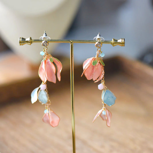 Florielle blush peach resin floral drop earrings with sage blue teardrops on a display stand
