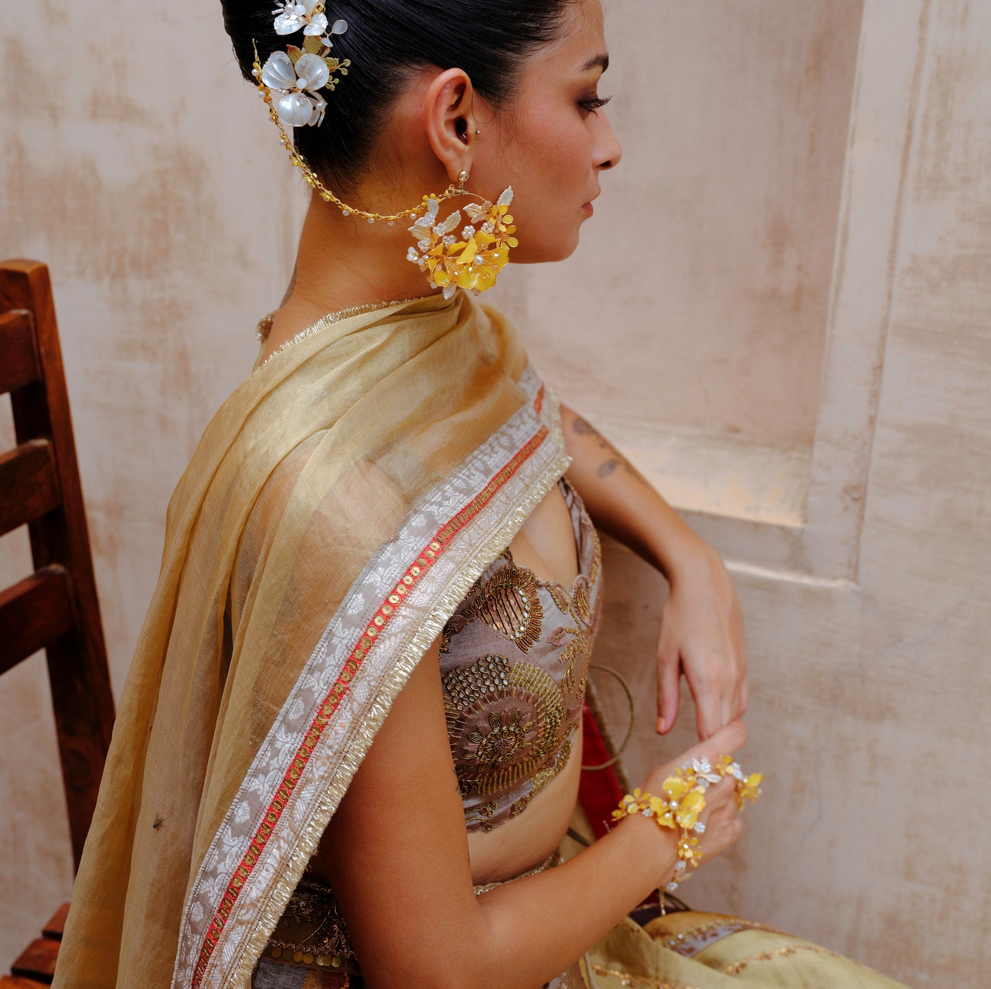 Model in ivory saree wearing Helios earrings with the hair harness trailing through her updo
