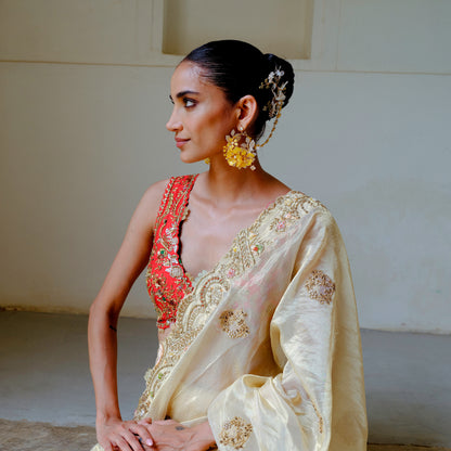 Model seated wearing Helios yellow floral earrings with hair harness in a festive look
