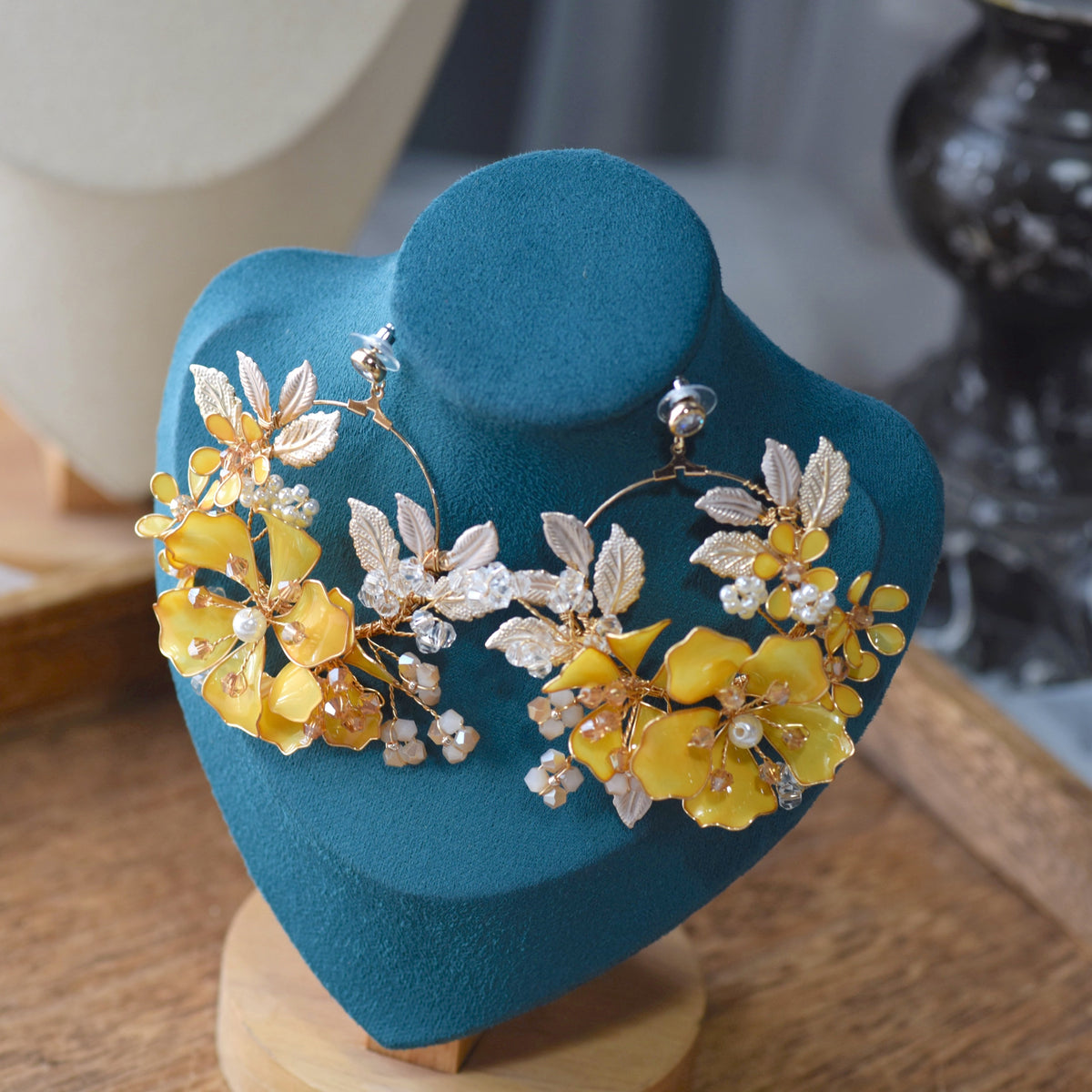 Helios yellow resin floral earrings with golden and ivory accents displayed on a stand
