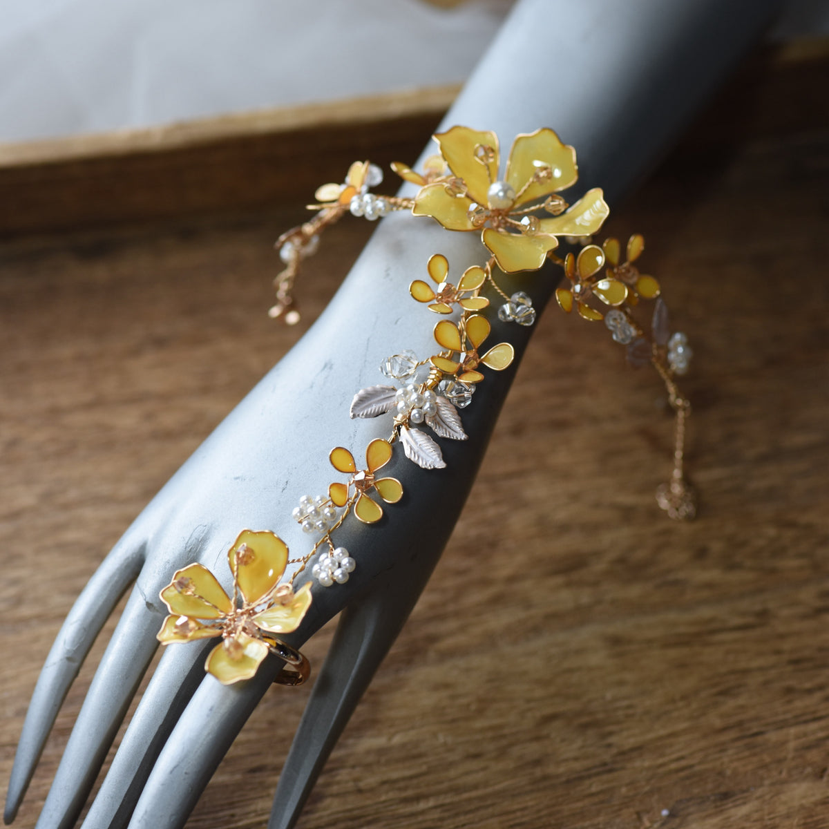 Helios yellow floral haath phool on a display hand showing the wrist-to-finger design
