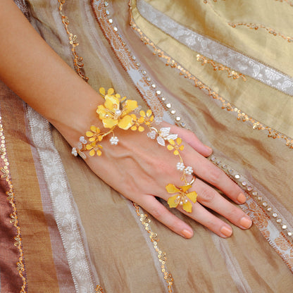 Helios yellow resin floral hand harness worn on the hand against a gold embroidered outfit
