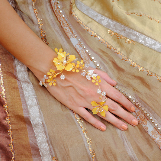 Helios yellow resin floral hand harness worn on the hand against a gold embroidered outfit
