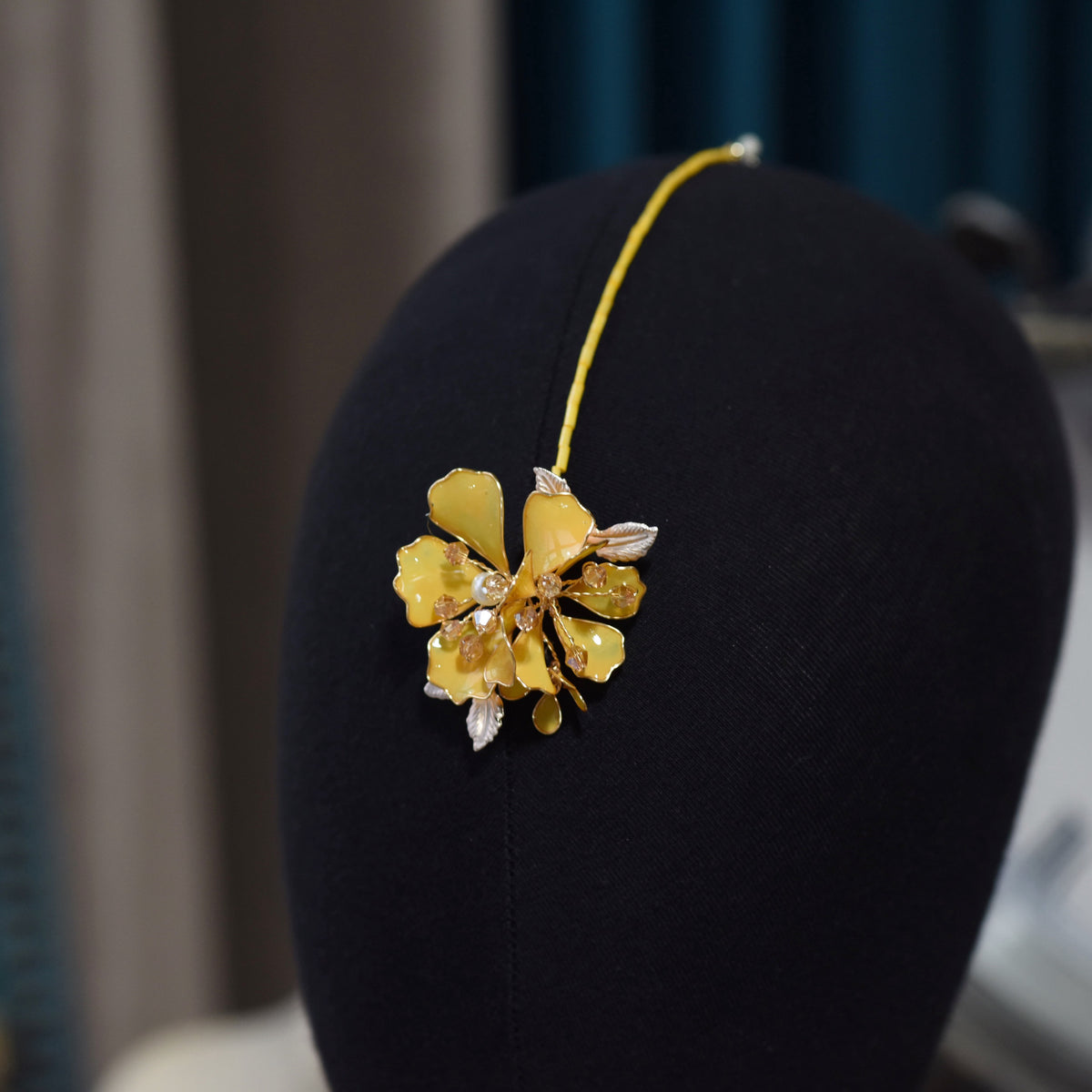 Close view of the Helios maang tika showing the yellow resin bloom and delicate golden chain
