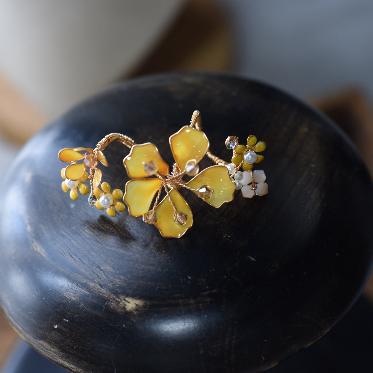 Close view of the Helios ring showing the yellow resin bloom and golden metallic petal detail
