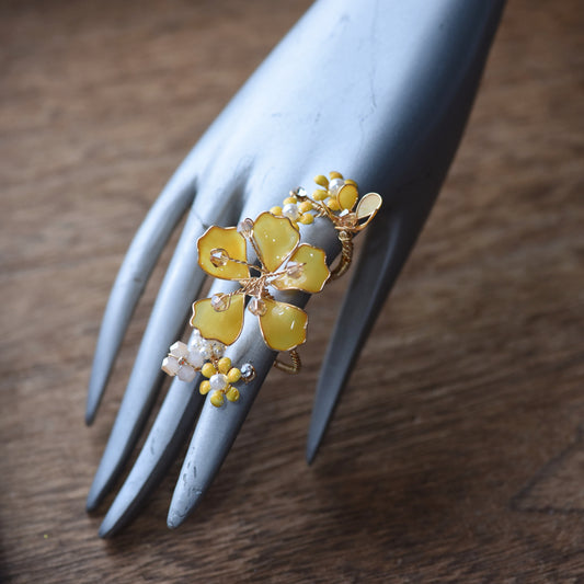 Helios yellow resin floral statement ring with golden accents on a display hand
