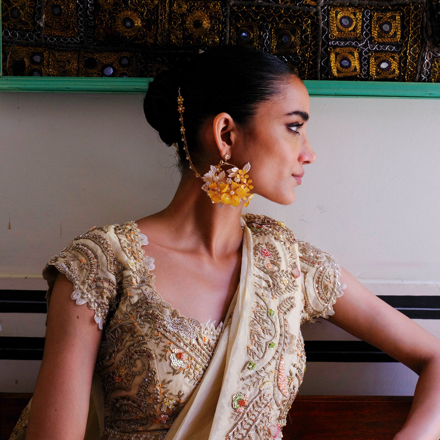 Side profile of model wearing Helios yellow floral earrings with golden accents

