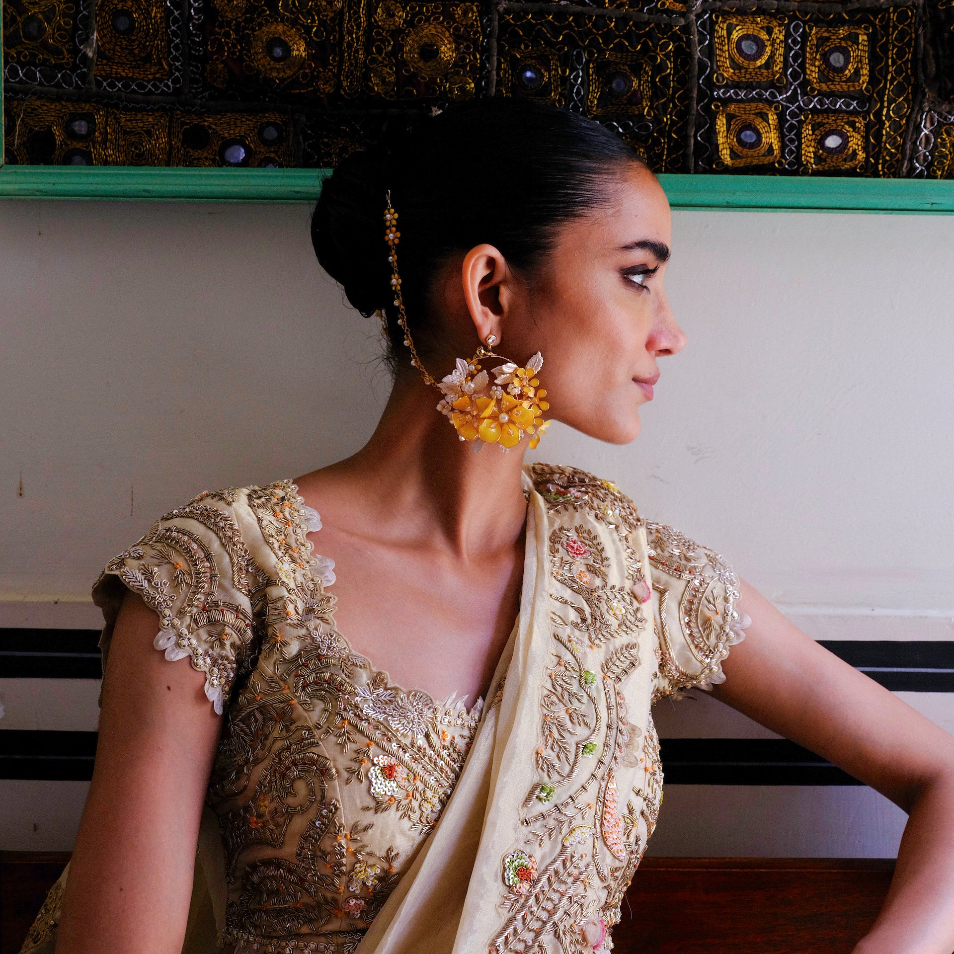 Side profile of model wearing Helios yellow floral earrings with golden accents

