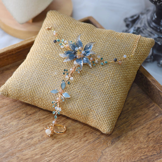 Iris periwinkle blue resin floral haath phool with pearl detailing on a jute cushion

