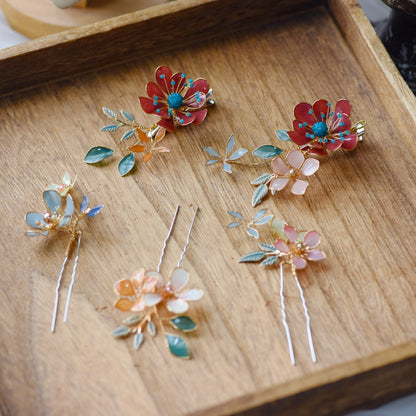 Isariah red ivory and green resin floral hair pins set of four laid on a wooden surface
