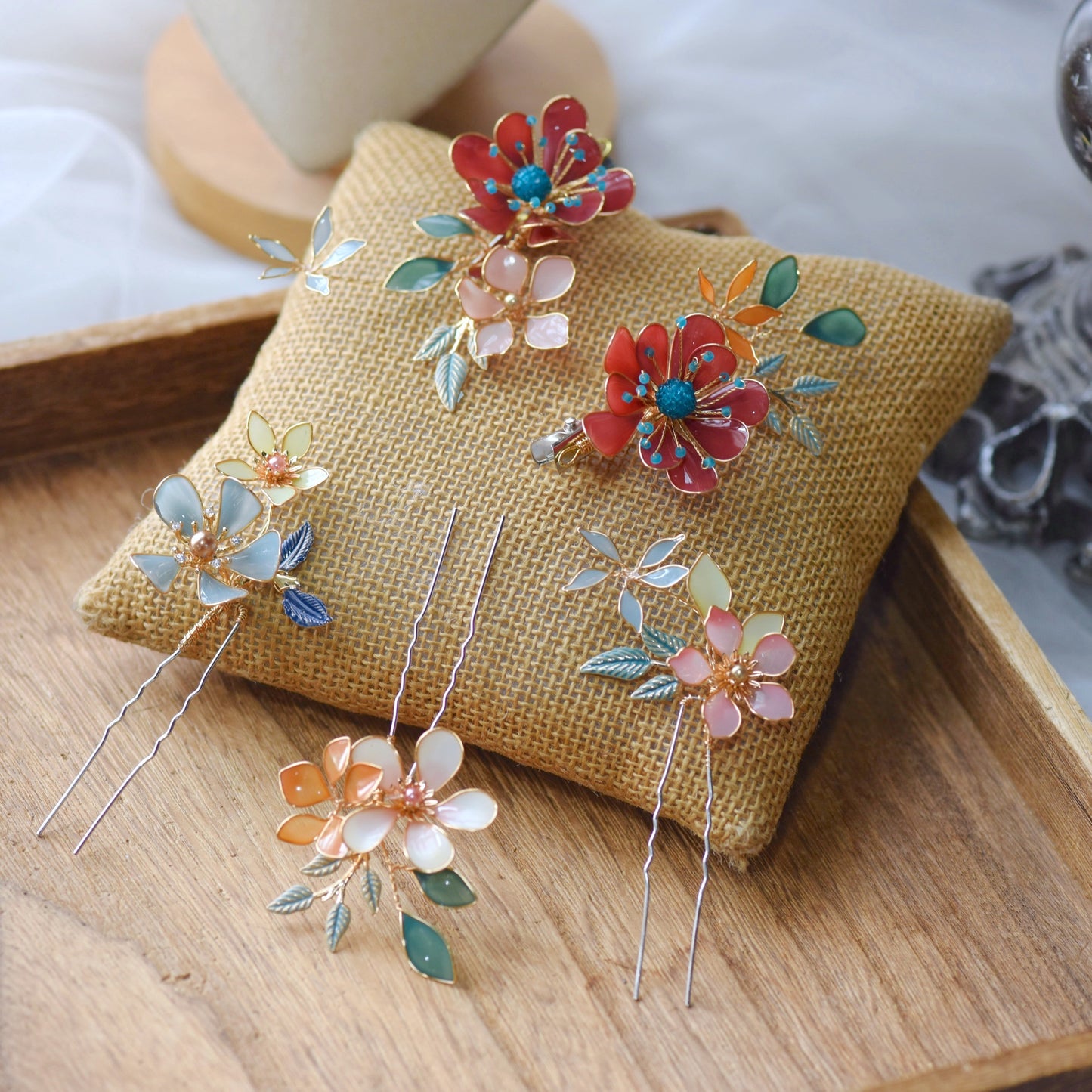 Isariah red and ivory resin floral hair pins with green leaves on an embroidered cushion
