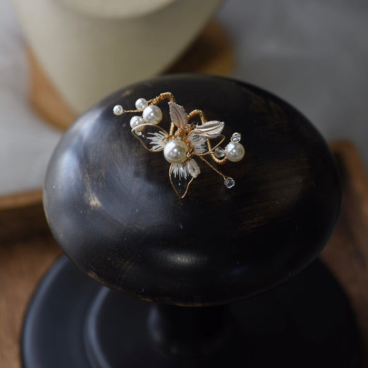 Juliana white resin floral bridal ring with imitation pearls and gold accents on display
