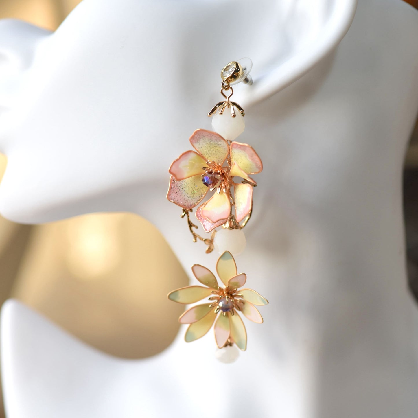 Close-up of Liliana pink and yellow resin floral earring with crystal centre and pearl beads
