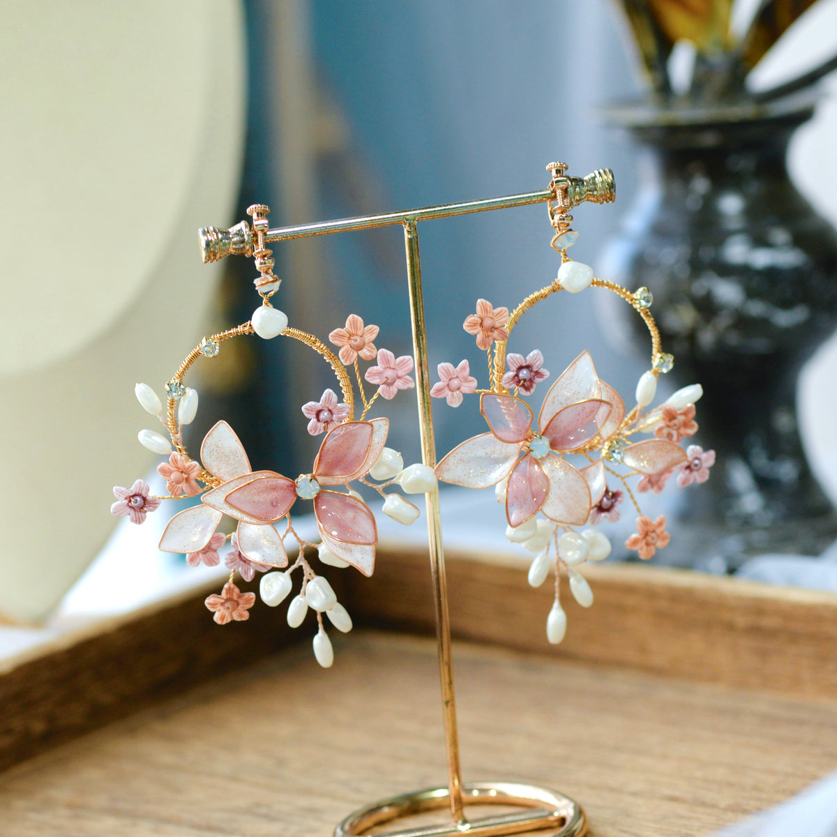 Madeline pink and lavender resin floral hoop earrings on golden hoop displayed on stand
