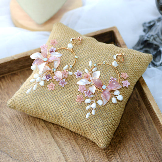Madeline pink white and lavender resin floral hoop earrings on jute cushion
