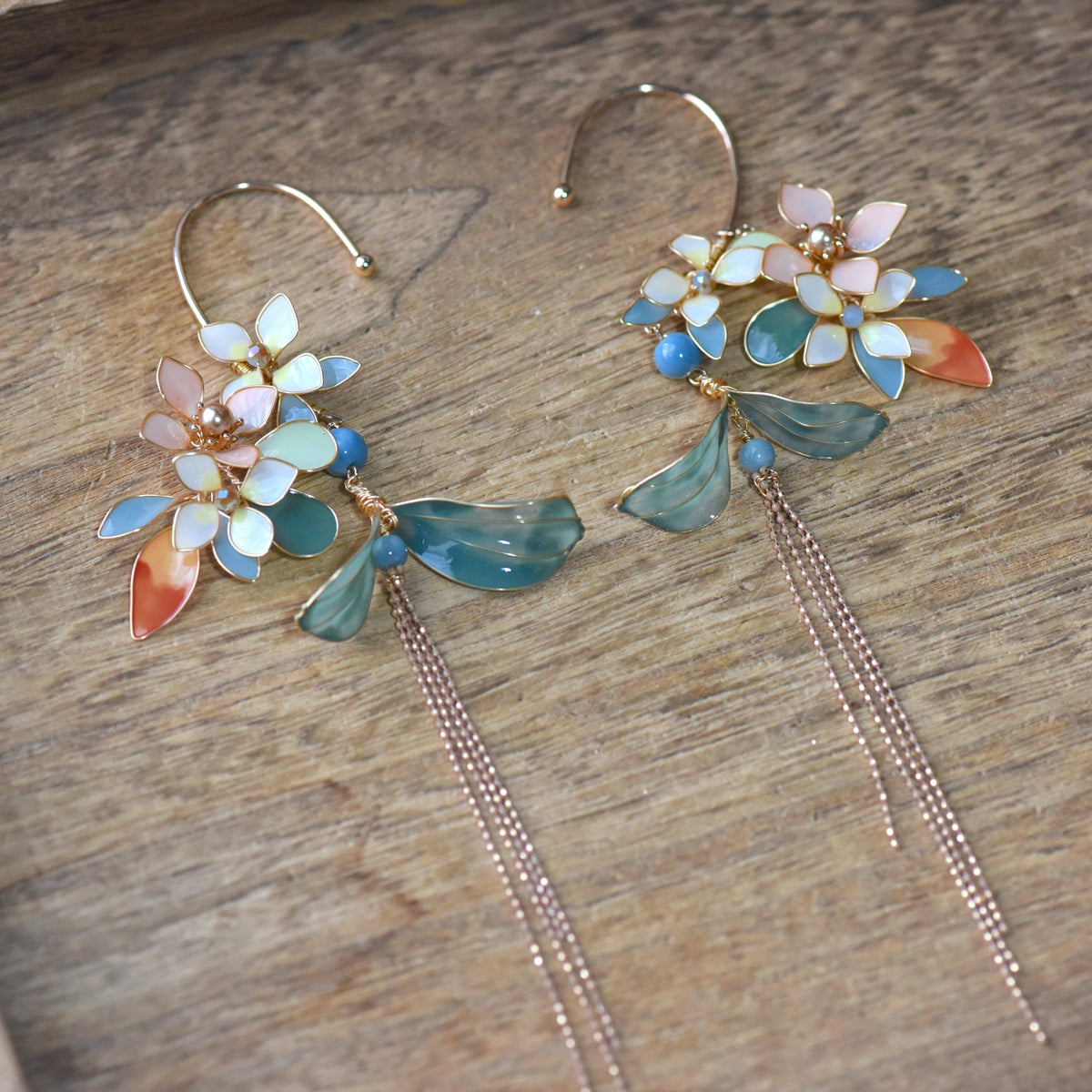 Mehr pastel resin floral ear cuffs pair with rose gold chains laid flat
