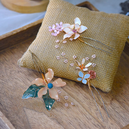 Micaela blush and ivory resin floral hair pins with sage leaves on a jute cushion
