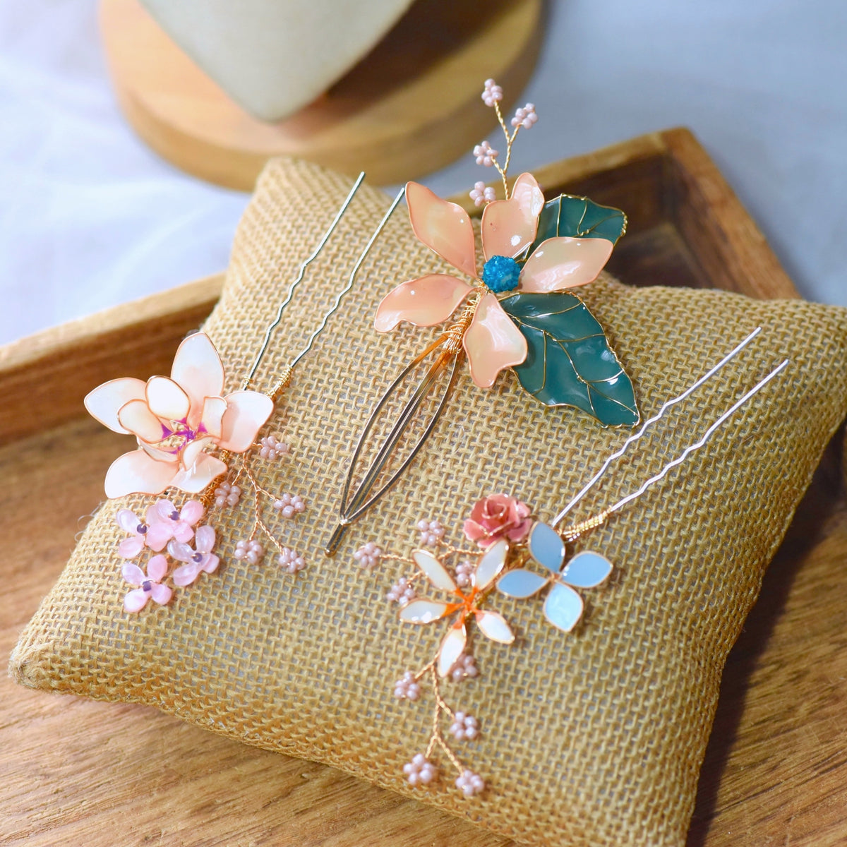 Micaela blush peach pastel blue and ivory resin floral hair pins on an embroidered cushion
