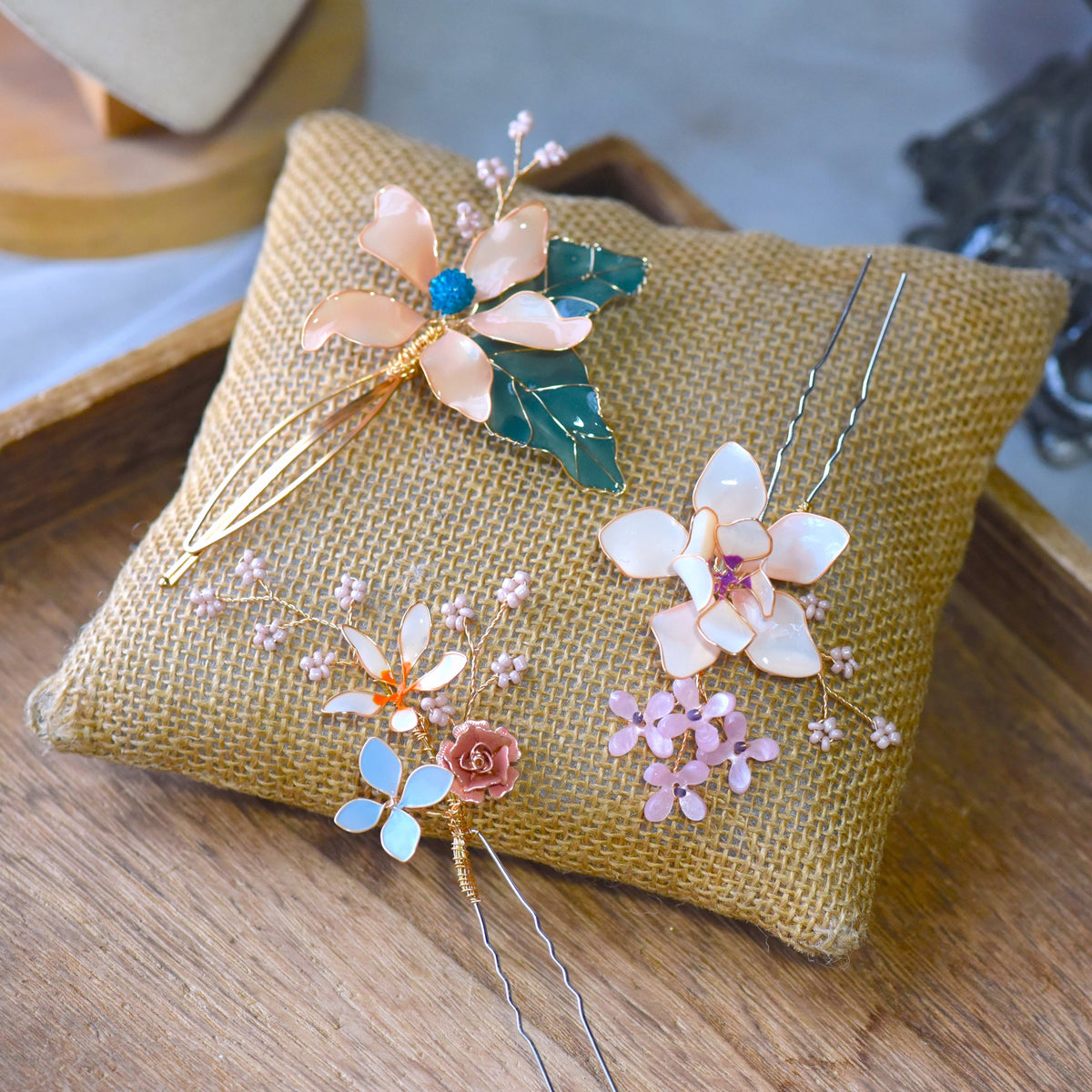 Micaela ivory and pastel blue resin floral hair pin detail showing bead clusters on a jute cushion