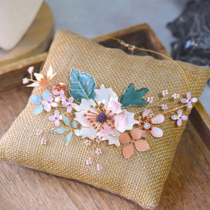 Micaela blush pink and peach resin floral necklace with green leaves on a jute cushion
