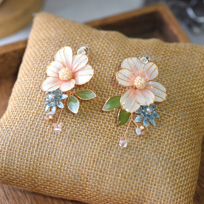 Milla blush peach resin floral earrings with sage green leaves and crystal drop on jute cushion
