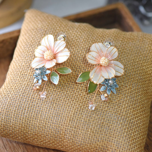 Milla blush peach resin floral earrings with sage green leaves and crystal drop on jute cushion
