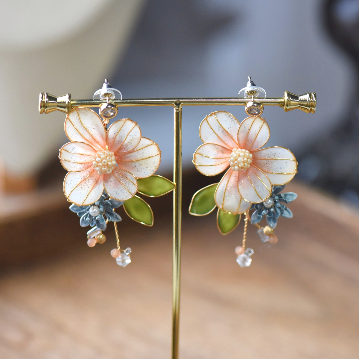 Milla blush peach resin floral earrings with pearl cluster centre on display stand
