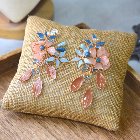 Nicola handcrafted floral resin earrings featuring blush peach and powder blue flowers with soft gold wire detailing