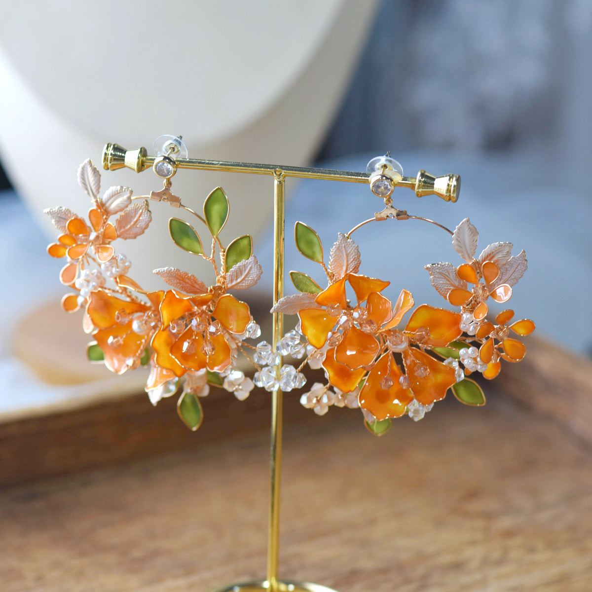 Orelia orange and green resin floral statement earrings on a display stand
