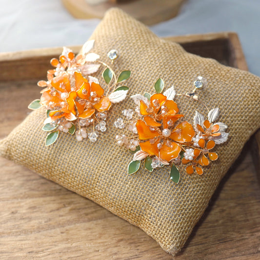 Orelia vivid orange resin floral earrings with green accents and gold leaves on a jute cushion
