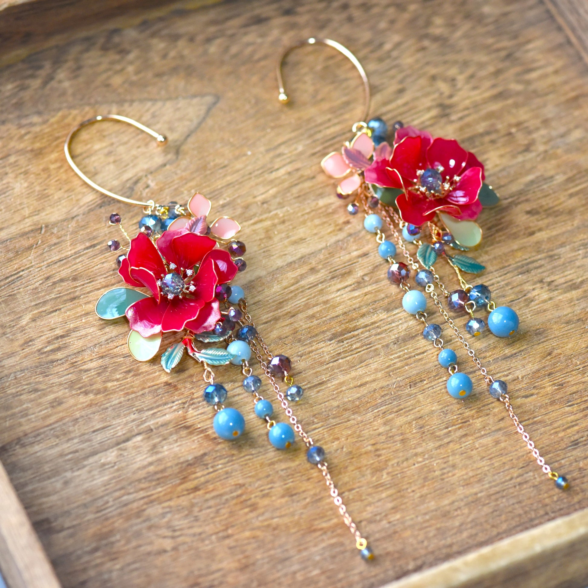Side view of Raphael ear cuff highlighting cascading blue bead drops, floral resin detailing and handcrafted gold wirework
