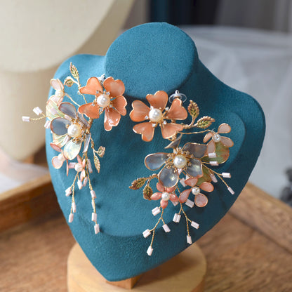 Reine blush and blue resin floral statement earrings displayed on a stand showing beaded sprig detail
