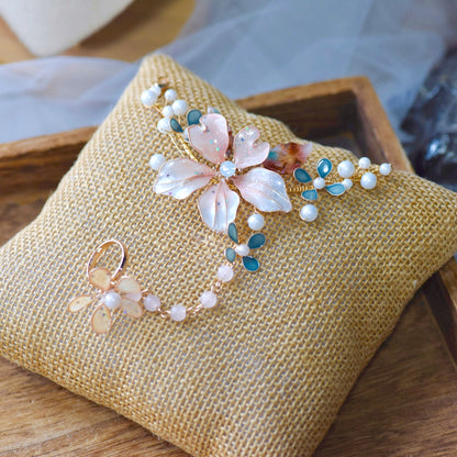 Rivia white and powder pink resin floral haath phool with pearl chains on a jute cushion
