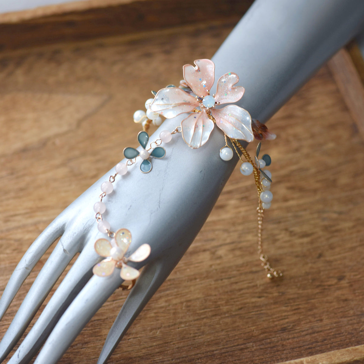 Rivia white and pink resin floral hand harness shown on a mannequin hand with adjustable ring and bracelet
