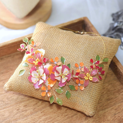 Samara handcrafted resin floral statement necklace vibrant pink orange red green gold on burlap cushion